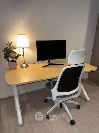 Modern home office setup with ergonomic chair and desk, featuring a sleek monitor and stylish lamp.