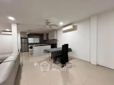 Spacious open-plan living and dining area with modern kitchen appliances and sleek design.