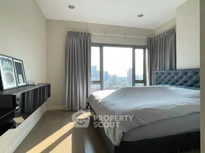 Modern bedroom with city view, featuring elegant decor and large windows for natural light.