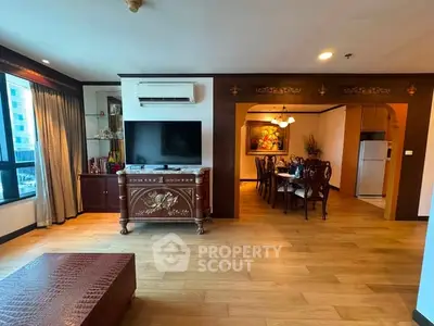 Spacious living room with elegant wooden flooring and classic furniture, adjacent to a dining area.