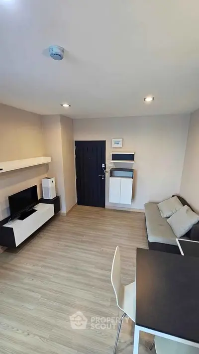 Modern living room with sleek furniture and wooden flooring, featuring a cozy sofa and wall-mounted shelves.