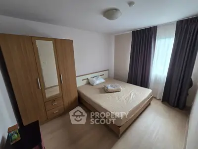 Cozy bedroom with wooden wardrobe and large window, perfect for relaxation.