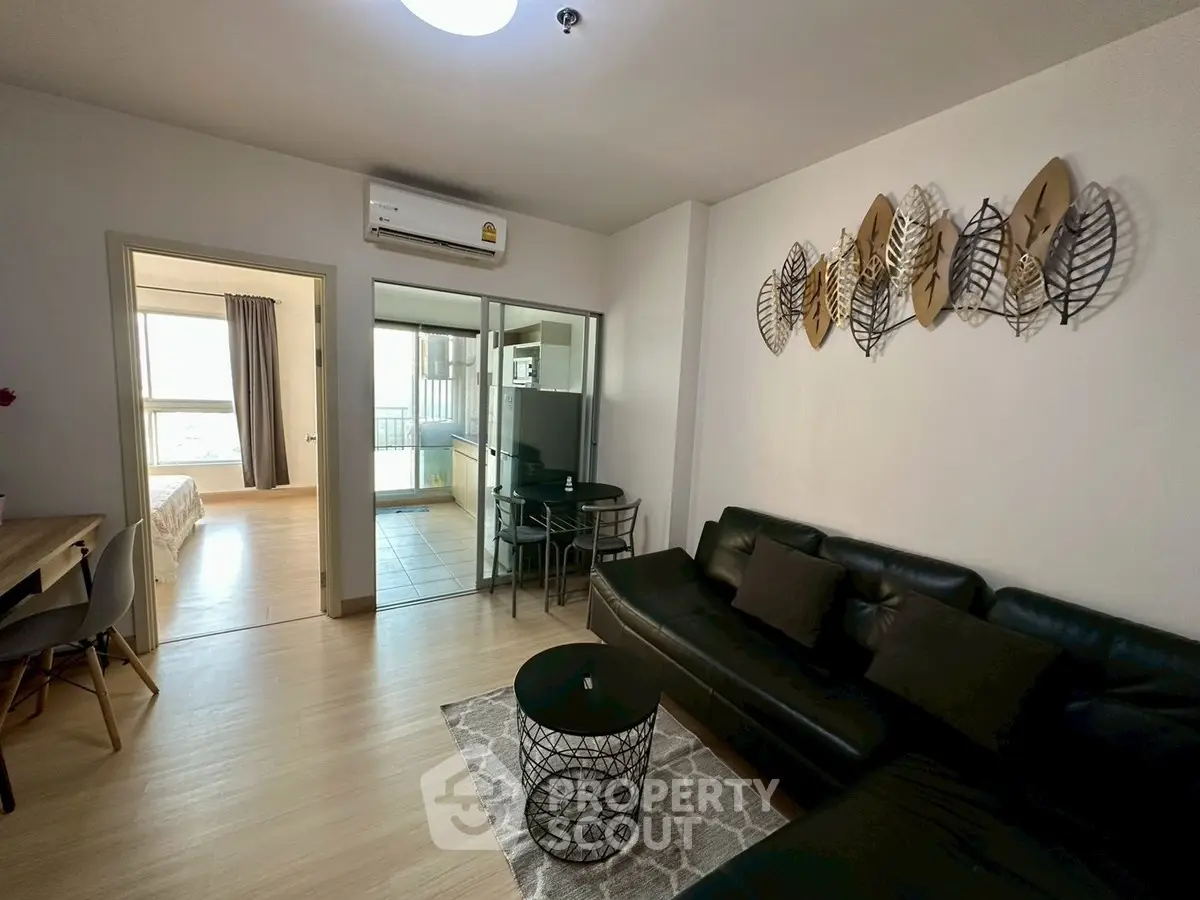 Modern living room with stylish decor and open layout leading to kitchen and bedroom.