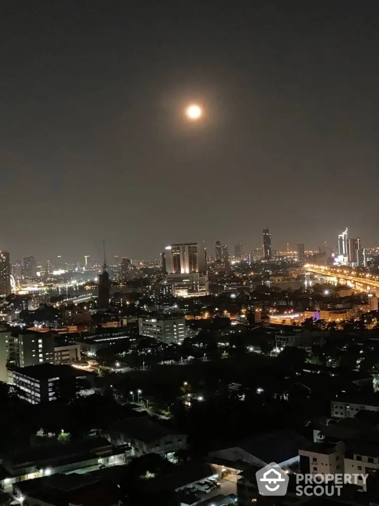 Stunning cityscape view at night with illuminated skyline and full moon.