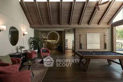 Luxurious living room with pool table and modern decor, featuring high wooden ceilings and stylish furniture.