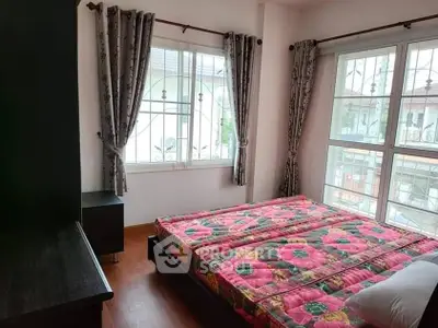Cozy bedroom with floral bedding and large windows for natural light.