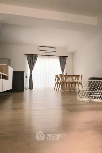 Spacious modern living room with wooden flooring and elegant dining area.