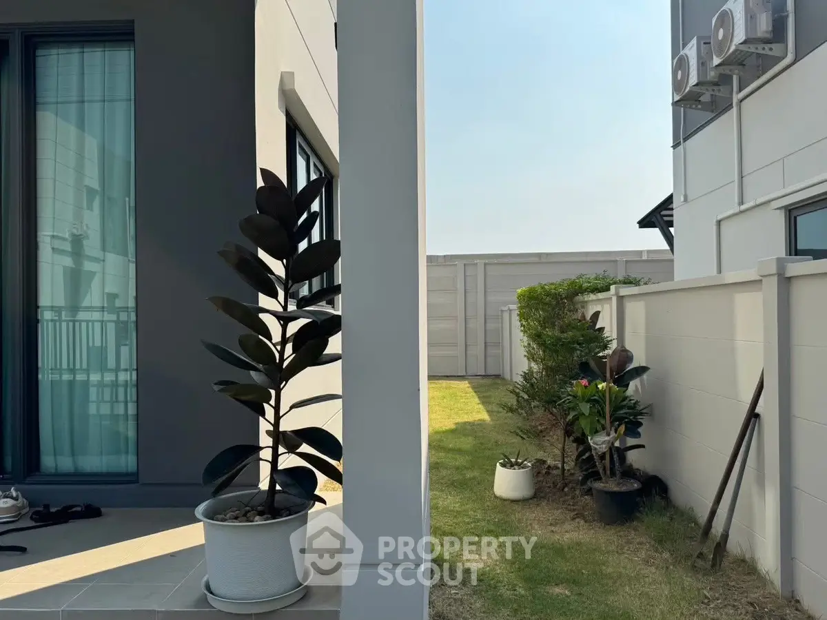 Modern exterior with garden and potted plants, showcasing sleek architecture and outdoor space.