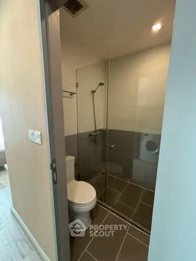Modern bathroom with glass shower and washing machine in compact layout.