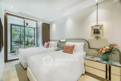 Luxurious bedroom with twin beds and elegant decor, featuring a view of a lush garden through sliding glass doors.