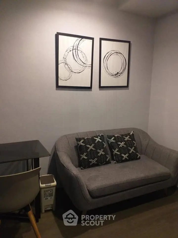 Cozy living room with modern gray sofa and abstract wall art, perfect for relaxation.