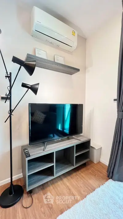 Modern living room corner with TV, stylish lamp, and air conditioning unit.
