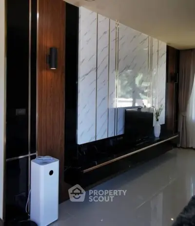 Luxurious modern living room with sleek black and wood paneling, featuring a large TV and elegant decor.