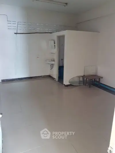 Spacious empty room with tiled floor and sink, ideal for customization.
