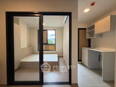 Modern apartment interior with open kitchen and cozy living area, featuring sleek wooden finishes and ample natural light.