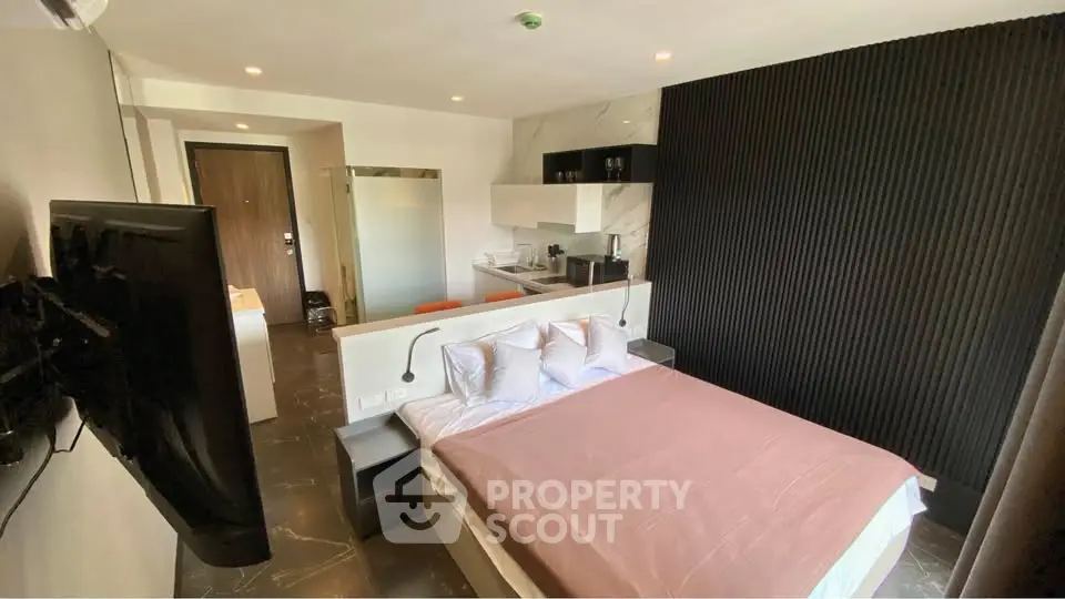 Modern studio apartment with stylish decor and open layout, featuring a cozy bed and sleek kitchenette.