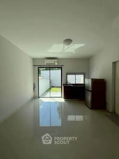 Bright minimalist living room with garden view and sleek tile flooring.