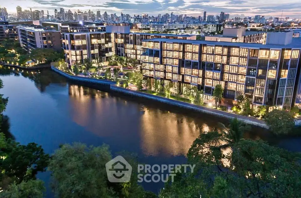 Luxurious riverside apartment complex with stunning city skyline views at dusk.