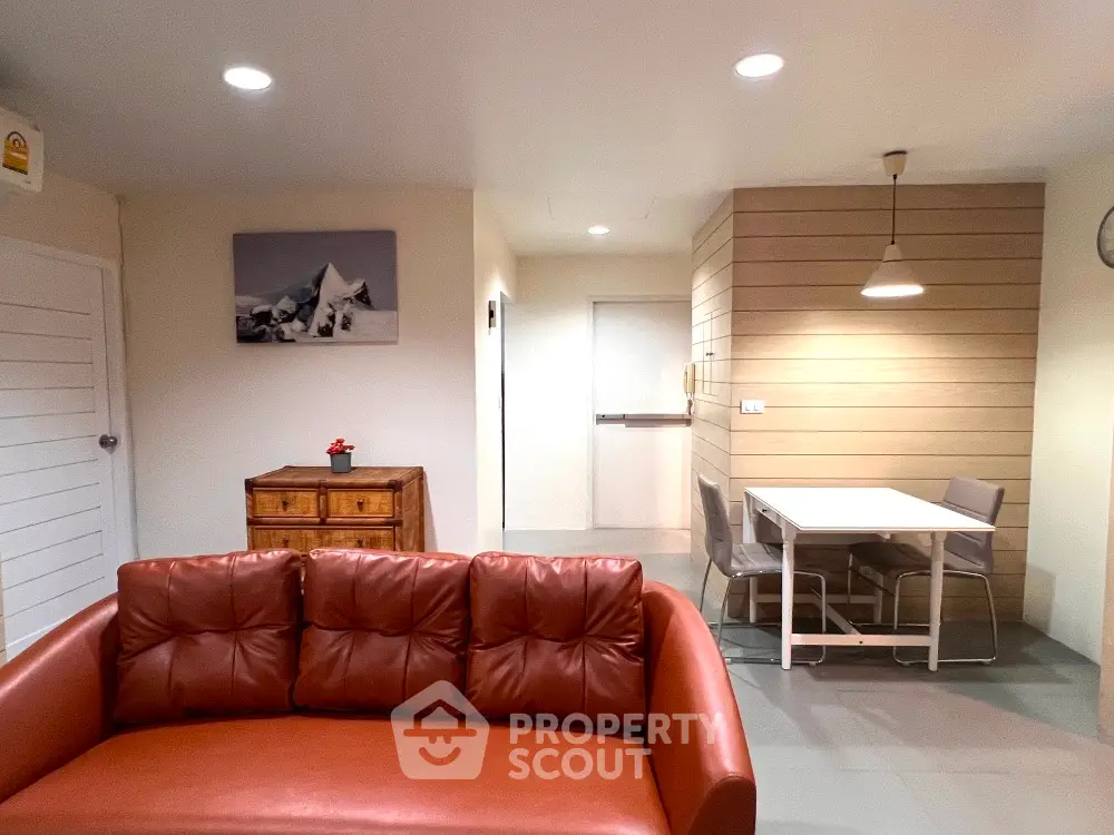 Modern living room with leather sofa and dining area, featuring stylish decor and ambient lighting.
