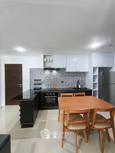 Modern kitchen with sleek black countertops and wooden dining set in open layout.