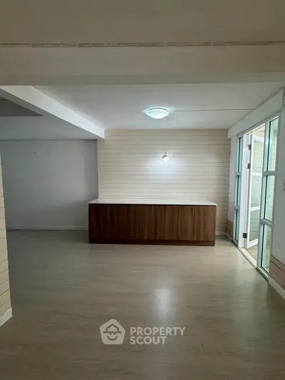 Spacious interior with wooden flooring and natural light, ideal for versatile living space.