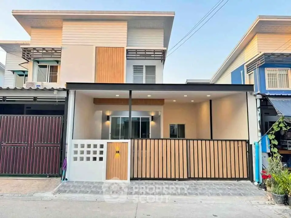 Modern two-story house with stylish facade and gated entrance in a suburban neighborhood.