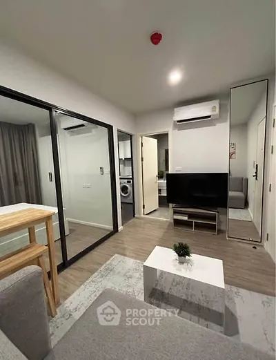 Modern living room with sleek design, featuring glass partitions, air conditioning, and a compact washing machine.