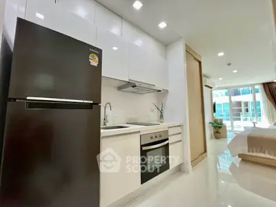 Modern kitchen with sleek appliances and open layout leading to a bright bedroom with large windows.