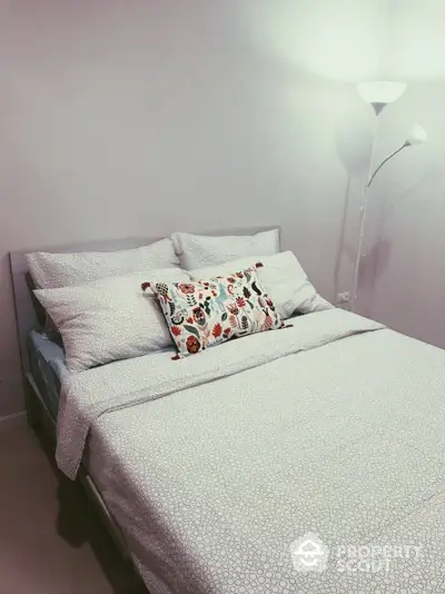 Cozy and inviting bedroom with a stylish patterned bedding set and a modern standing lamp, perfect for restful nights in a chic urban home.