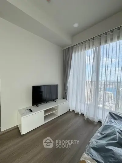 Modern living room with large window and city view, featuring sleek TV stand and hardwood floors.