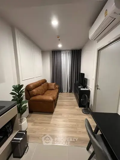 Modern living room with brown leather sofa, sleek TV setup, and stylish decor in a cozy apartment.