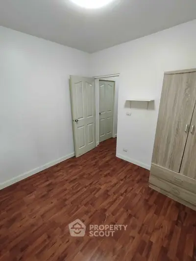 Spacious empty bedroom with wooden flooring and wardrobe, ready for customization.