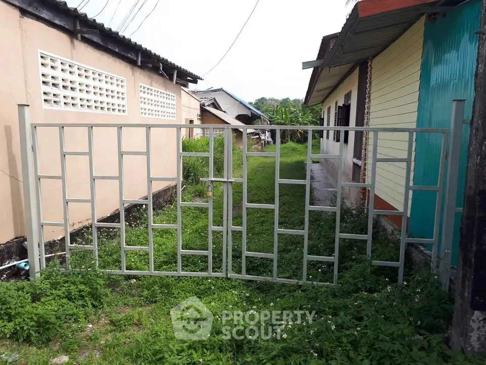 Residential property with metal gate and lush green surroundings