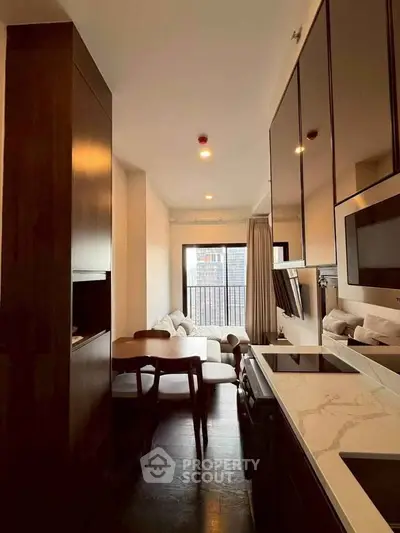 Modern apartment interior with sleek kitchen and cozy living area, featuring stylish furniture and large windows.