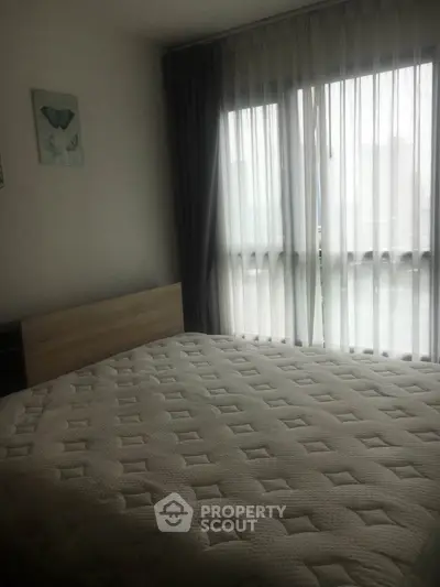 Cozy bedroom with large window and modern decor, perfect for relaxation and comfort.