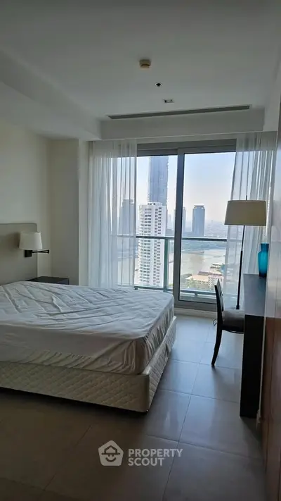 Spacious bedroom with stunning city view and modern furnishings in a high-rise apartment.