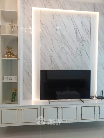 Luxurious living room with marble wall and modern TV setup, elegant decor and built-in shelving.