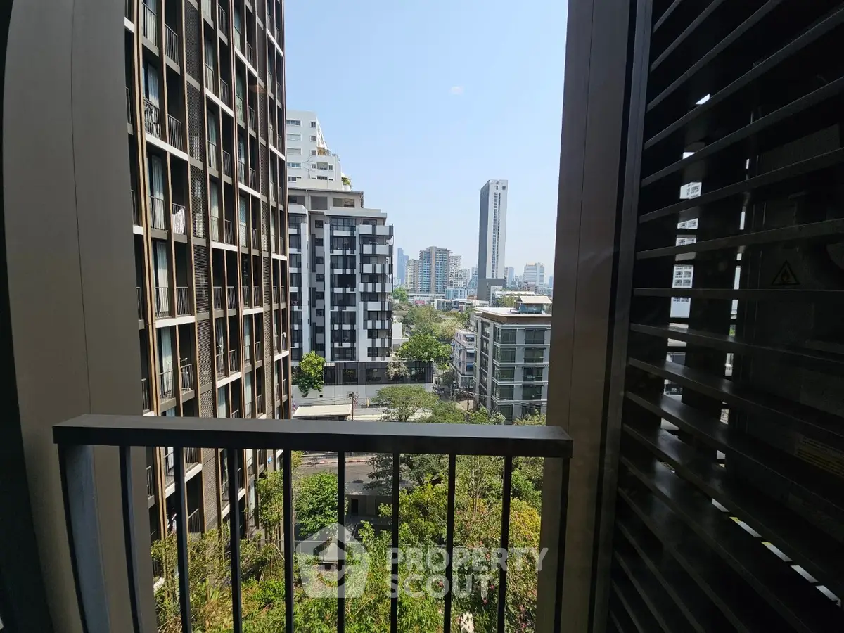 Stunning urban view from a high-rise balcony overlooking modern cityscape and lush greenery.