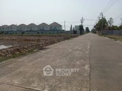 Spacious suburban road leading to modern residential houses with clear skies.