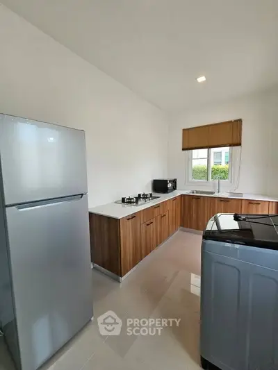 Modern kitchen with sleek appliances and wooden cabinetry in a bright, spacious layout.