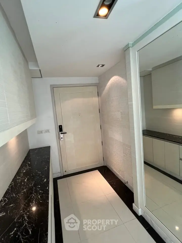 Modern apartment entrance with sleek marble countertops and elegant lighting.