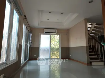 Spacious living room with large windows and modern staircase, perfect for natural light lovers.