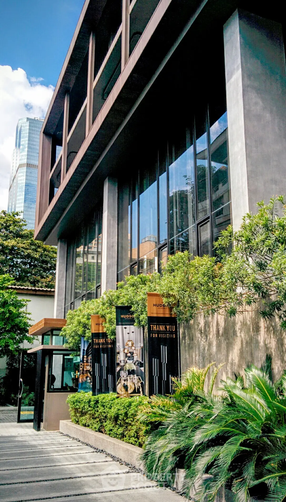 Modern building exterior with lush greenery and urban skyline view.