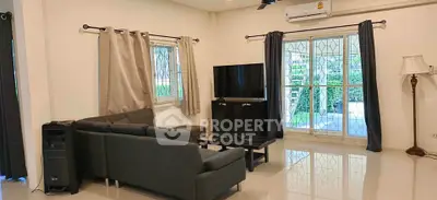 Spacious living room with modern furniture and large windows offering garden views.