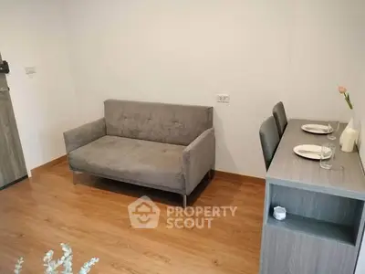 Cozy living room with modern sofa and dining table, perfect for small apartments.