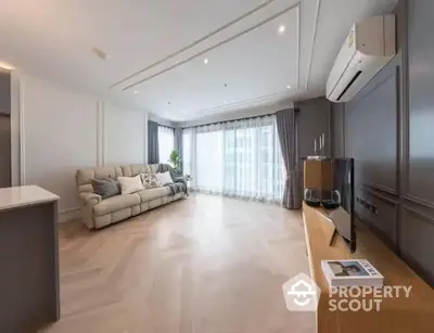 Spacious modern living room with ample natural light, elegant hardwood flooring, and a cozy beige sofa set, perfect for comfortable urban living.