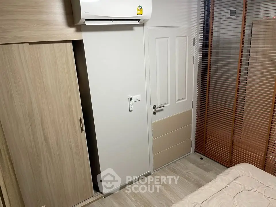 Cozy bedroom with modern air conditioning and wooden wardrobe, perfect for comfortable living.