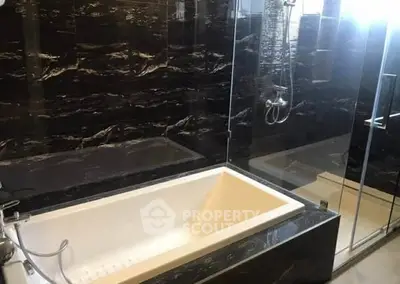 Luxurious bathroom with sleek black marble tiles and modern bathtub.