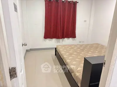 Cozy bedroom with red curtains and a comfortable bed in a minimalist setting.