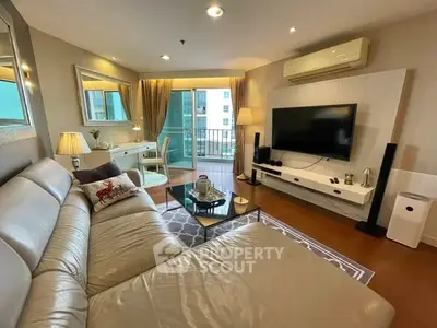 Spacious modern living room with leather sofa and large TV, featuring a balcony view.